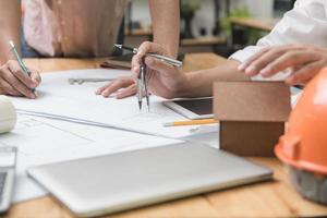 equipo de arquitectos o ingenieros discutiendo en el escritorio con planos sobre el nuevo proyecto de inicio en el escritorio. grupo de equipo en los documentos de verificación del sitio de construcción y el flujo de trabajo comercial. enfoque selectivo. foto