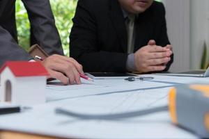 equipo de arquitectos o ingenieros discutiendo en el escritorio con planos sobre el nuevo proyecto de inicio en el escritorio. grupo de equipo en los documentos de verificación del sitio de construcción y el flujo de trabajo comercial. enfoque selectivo. foto