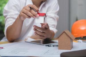 equipo de arquitectos o ingenieros discutiendo en el escritorio con planos sobre el nuevo proyecto de inicio en el escritorio. grupo de equipo en los documentos de verificación del sitio de construcción y el flujo de trabajo comercial. enfoque selectivo. foto