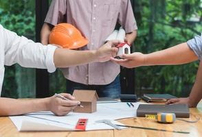 equipo de arquitectos o ingenieros discutiendo en el escritorio con planos sobre el nuevo proyecto de inicio en el escritorio. grupo de equipo en los documentos de verificación del sitio de construcción y el flujo de trabajo comercial. enfoque selectivo. foto