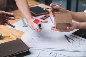 equipo de arquitectos o ingenieros discutiendo en el escritorio con planos sobre el nuevo proyecto de inicio en el escritorio. grupo de equipo en los documentos de verificación del sitio de construcción y el flujo de trabajo comercial. enfoque selectivo. foto