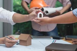 equipo de arquitectos o ingenieros discutiendo en el escritorio con planos sobre el nuevo proyecto de inicio en el escritorio. grupo de equipo en los documentos de verificación del sitio de construcción y el flujo de trabajo comercial. enfoque selectivo. foto