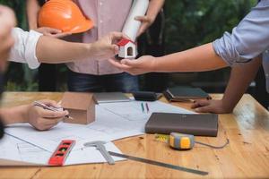 equipo de arquitectos o ingenieros discutiendo en el escritorio con planos sobre el nuevo proyecto de inicio en el escritorio. grupo de equipo en los documentos de verificación del sitio de construcción y el flujo de trabajo comercial. enfoque selectivo. foto