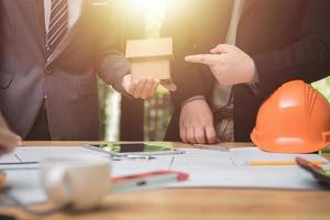 equipo de arquitectos o ingenieros discutiendo en el escritorio con planos sobre el nuevo proyecto de inicio en el escritorio. grupo de equipo en los documentos de verificación del sitio de construcción y el flujo de trabajo comercial. enfoque selectivo. foto