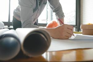 manos de arquitecto o ingeniero usando brújula de dibujo con plano en el escritorio en la oficina. equipo de arquitectos ingenieros discutiendo y verificando documentos y flujo de trabajo empresarial. concepto de construcción. foto