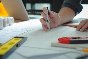 Hands of architect or engineer using drawing compass with blueprint on desk in office.Team of architects engineer discussing and check documents and business workflow.Construction concept. photo