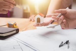 equipo de arquitectos o ingenieros discutiendo en el escritorio con planos sobre el nuevo proyecto de inicio en el escritorio. grupo de equipo en los documentos de verificación del sitio de construcción y el flujo de trabajo comercial. enfoque selectivo. foto