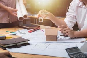 equipo de arquitectos o ingenieros discutiendo en el escritorio con planos sobre el nuevo proyecto de inicio en el escritorio. grupo de equipo en los documentos de verificación del sitio de construcción y el flujo de trabajo comercial. enfoque selectivo. foto