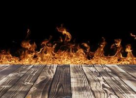 The slant top view of the wooden floor on a black background with flames in the background and can be used to showcase or edit your products. photo