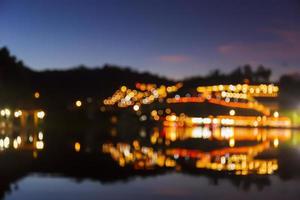 Abstract colorful bokeh of light bulbs and city skyline from river at sunset. photo