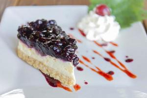 Blueberry cheesecake is arranged in a beautiful plate on wooden table background. photo