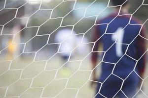 Goalkeeper stands against goal with net and stadium. Football gate net. Behind goal of soccer field. photo