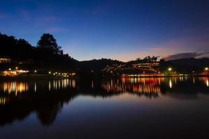 mae hong son tailandia 31 de octubre de 2021 baan rak pueblo tailandés luz de las lámparas que se reflejan en el crepúsculo del atardecer del río. foto