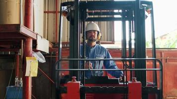 trabalhador industrial asiático masculino uniforme de segurança e capacete de segurança usam empilhadeira hidráulica, transporte e transporte logístico na fábrica de fabricação de armazém, estoques de fornecimento ocupação de motorista profissional. video