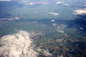 foto aérea desde la ventana del avión, sobre el suelo y la nube, campo verde bajo las nubes