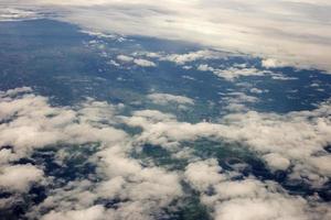 aerial photo from window of plane, above ground and cloud, green field under the clouds