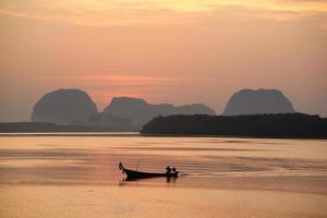 hermosa vista en la mañana durante el amanecer y el bote de cola larga de pescador foto