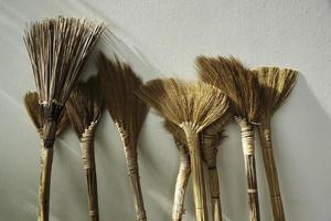 Several brooms placed against the wall photo