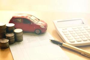 pila de monedas en columnas, libro de ahorro, coche. concepto de finanzas y banca. foto