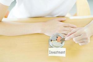 Woman hands with coins in glass jar, top view photo