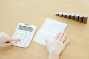 Businesswoman use calculator beside passbook and Coins photo