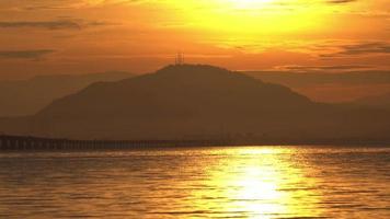 Silhouette morning sunrise of car move at the Penang Bridge across the sea. Background is Cherok Tokkun hill. video