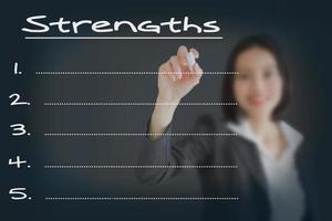 Beautiful businesswoman writing list of business strength photo