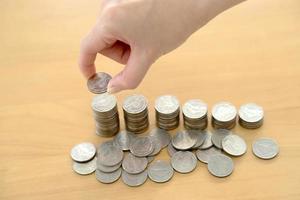 woman put coins to stack of coins photo