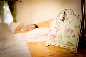 Young woman sleeping in bed with alarm at night photo