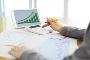 Close-up Of Businesswoman Holding Digital Tablet With Graphs On Desk photo