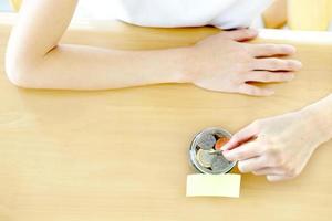 Woman hands with coins in glass jar, top view photo