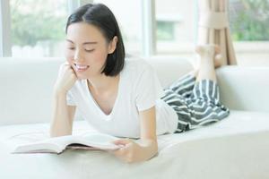 retrato de una mujer relajada e informal leyendo un libro en un sofá en una casa luminosa foto