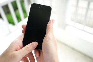 mujer con teléfono móvil moderno en las manos tocando una pantalla en blanco. foto