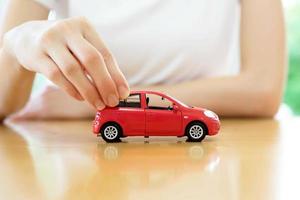 mujer de negocios junto a un escritorio que sostiene un coche de juguete. foto