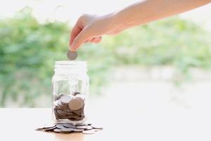 Woman Dropping Coins Into Glass Jar photo