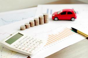 With Car Model And Stack Of Coins On Desk photo