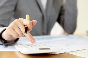 Young Businesswoman Analyzing Report On Chart With Calculator photo