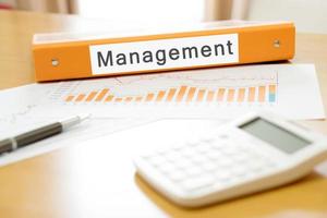 Orange  binder debtor on desk in the office with calculator and pen photo