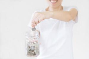 business, finance, saving, banking and people concept - close up of woman hands putting us dollar money into glass mason jar photo