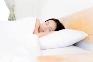 A woman resting in bed with hands beside her head on the pillow. photo