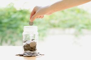 Woman Dropping Coins Into Glass Jar photo