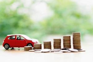 Stacks of giant silver coins next to a new red car photo