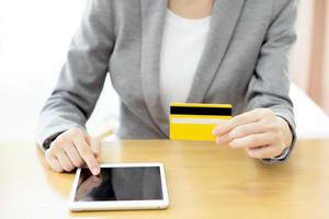 Close-up woman's hands holding a credit card and using tablet pc photo