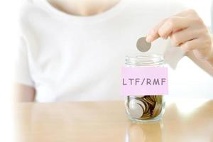 Woman hands with coins in glass jar, close up photo