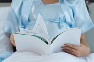 Pregnant woman in bedroom reading fairy tales to the baby in the womb in the morning photo