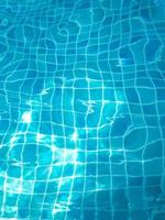 The water in the swimming pool with light reflecting the bottom of the pool is a blue checkerboard tile. photo