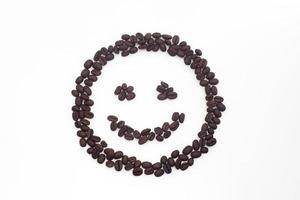 Roasted coffee beans arranged in a smiling face on a white background. photo