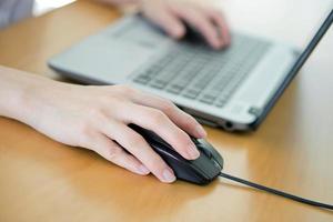 Female hand with computer mouse on table, closeup photo