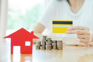 inversión inmobiliaria con tarjeta de crédito. casa y monedas en la mesa. foto
