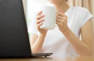 Young businesswoman drinking coffee and using laptop photo